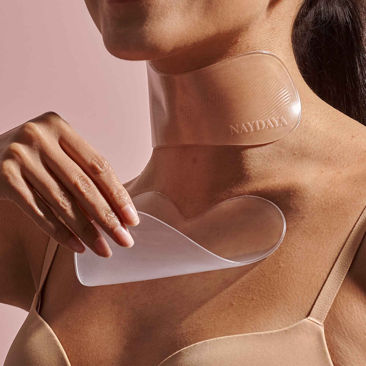 Person applying a neck wrap labelled 'NAYDAYA' on a pink background