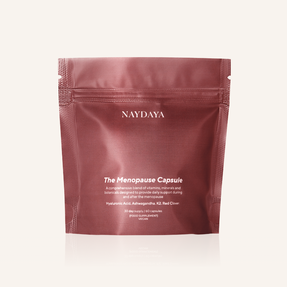 A matte burgundy stand-up pouch of NAYDAYA The Menopause Capsule, photographed against a clean off-white background with a subtle reflection.