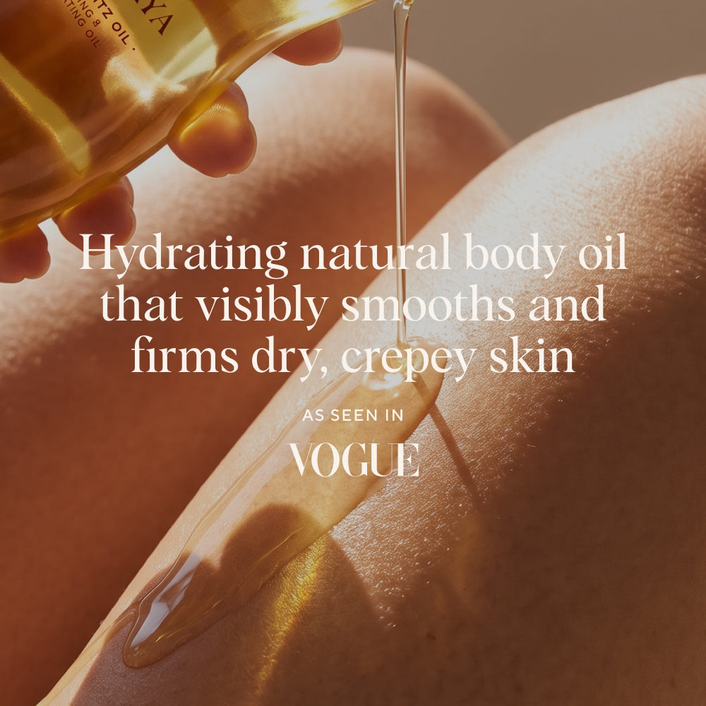 A close-up of a hand pouring Naydaya Body Blitz body oil onto skin, with overlaid text reading 'Hydrating natural body oil that visibly smooths and firms dry, crepey skin' and 'AS SEEN IN Vogue'.