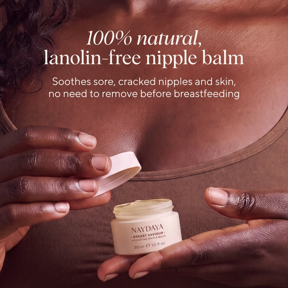 A close-up of a person holding an open cream jar labeled NAYDAYA Breast Saviour while applying or holding the open lid near their chest. Text on the image reads: '100% natural, lanolin-free nipple balm' and 'Soothes sore, cracked nipples and skin, no need to remove before breastfeeding.