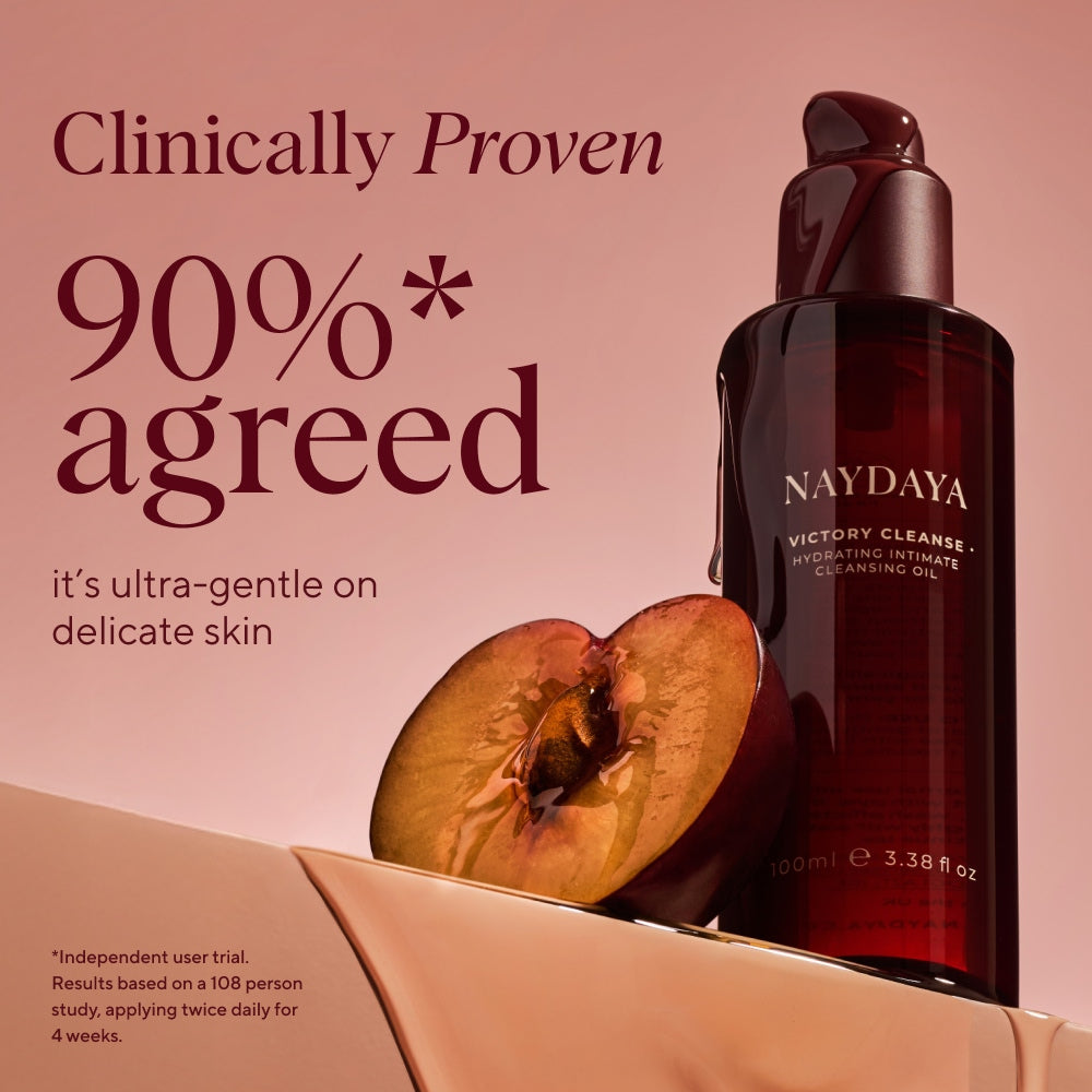 Naydaya Victory Cleanse Wash 100ml bottle in a dark amber glass pump bottle, displayed next to a halved peach on a beige platform against a dusty rose background with 'clinically proven' text.